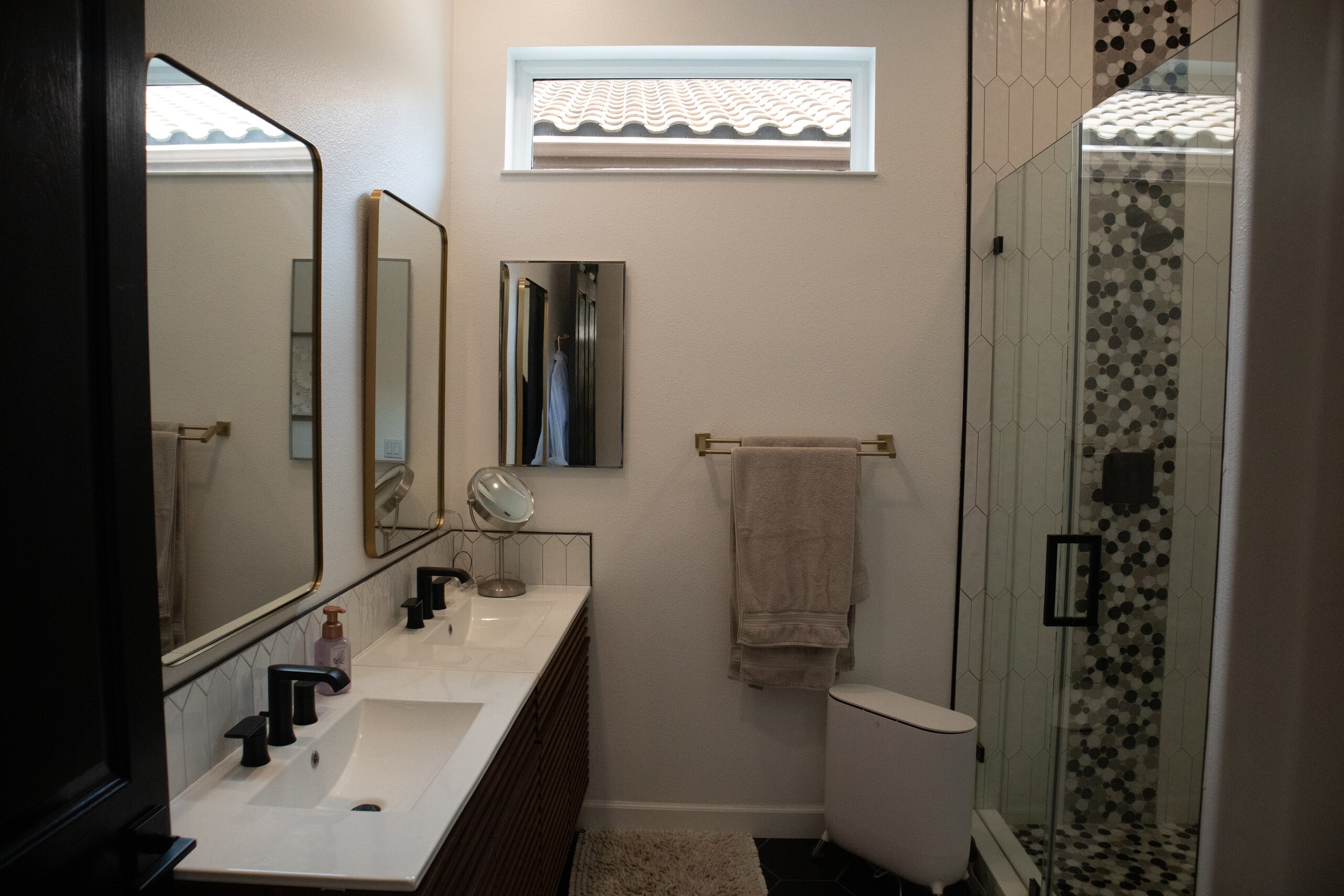 Remodeled bathroom with black-and-white tile and warm wood vanity